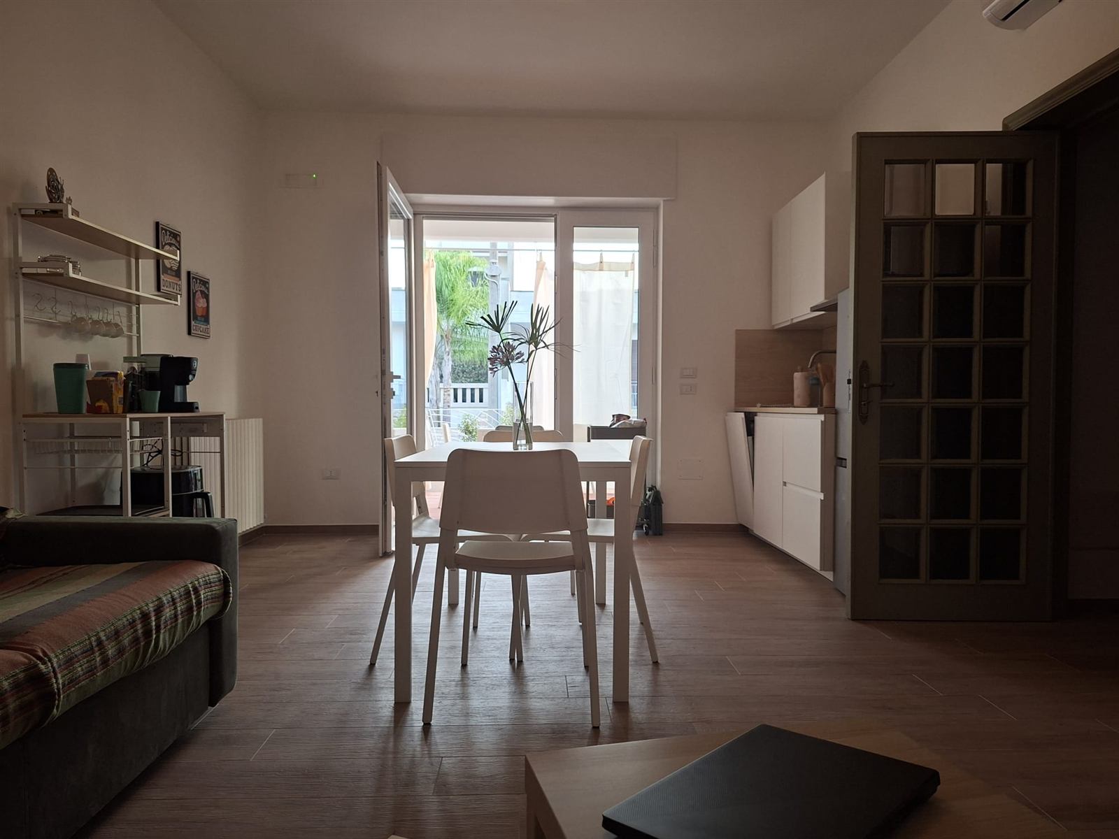 Living luminoso di Casa Copé con tavolo, divano e accesso alla terrazza